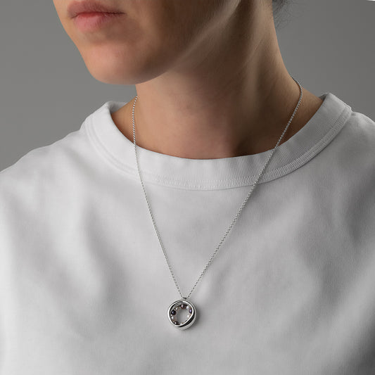 14KT white gold necklace with a circular, organic pendant featuring black and white pearls worn around the neck.