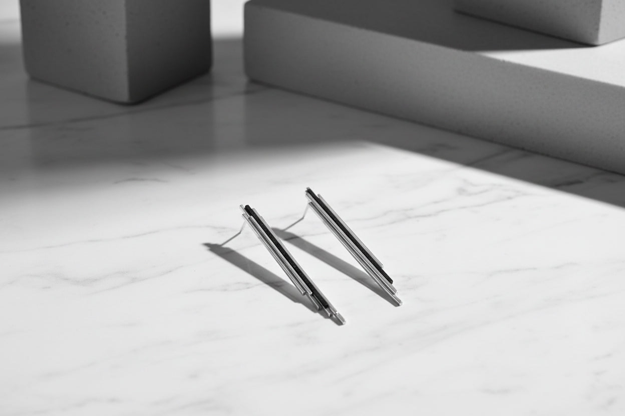 Skyline earrings sterling silver with ebony wood. A pair of silver earrings with a geometric design, featuring a slender vertical element.